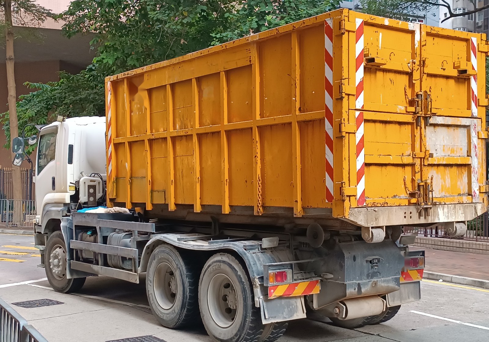 Large roll-off truck carrying a loaded steel container on a residential street