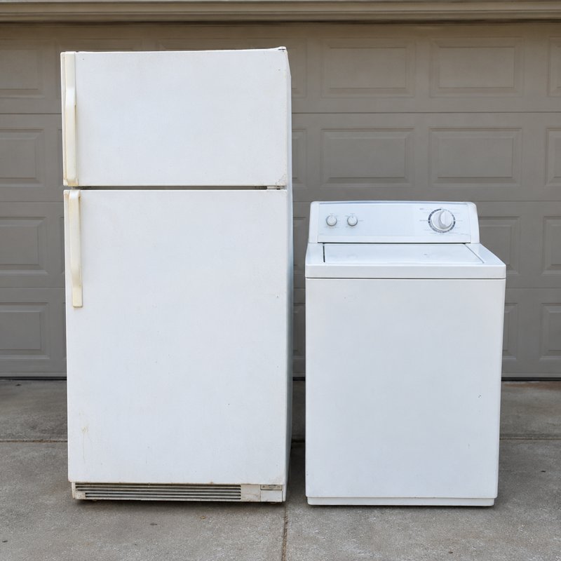 A refrigerator and washer set beside a dump trailer