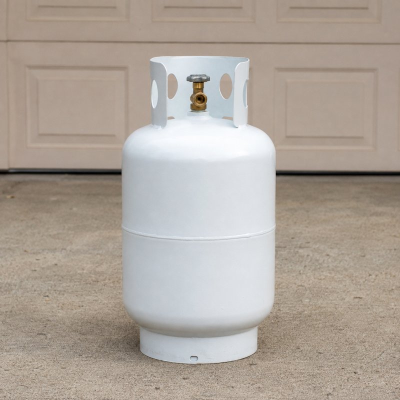 A propane cylinder standing beside a dump trailer